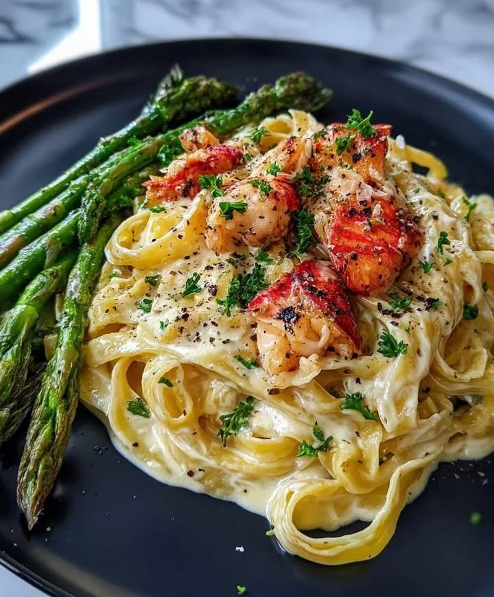 Creamy Lobster Alfredo served with roasted asparagus on a plate