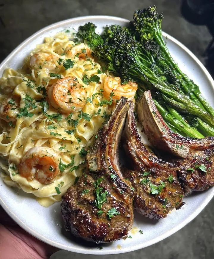 Garlic Lamb Chops served with Shrimp Alfredo and Roasted Broccolini on a plate