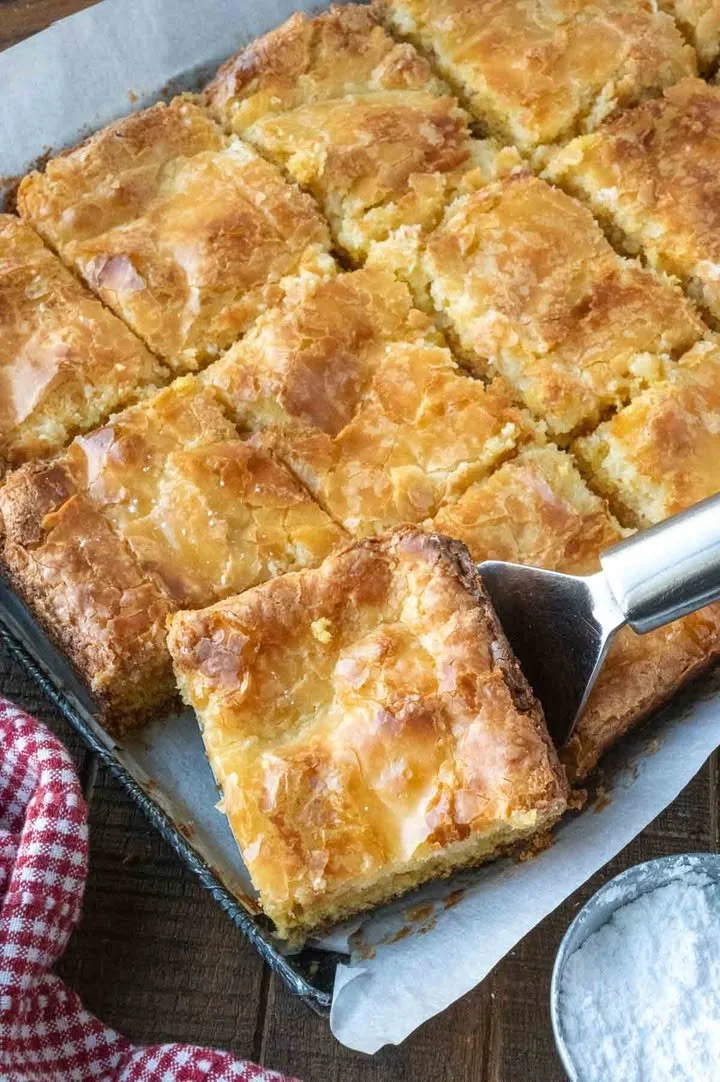 Delicious Gooey Butter Cake Bars topped with powdered sugar on a plate